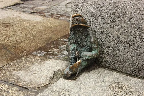 Spioch the sleeping dwarf curled up on a Wroclaw sidewalk